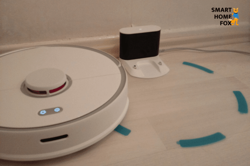 The Roborock S5 Max stands at the charging dock with the transparent plastic mat as a water protection pad